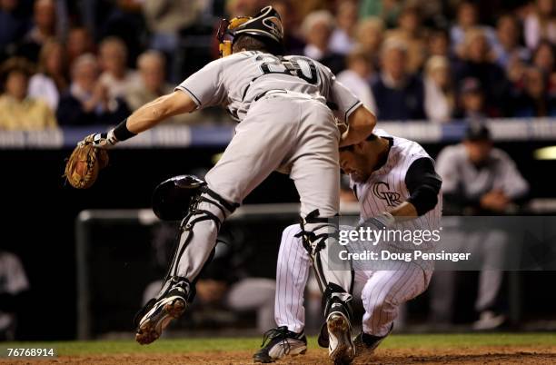 Jamey Carroll of the Colorado Rockies collides with catcher Matt Treanor of the Florida Marlins as Carroll scored on a single by pitcher Josh Fogg to...