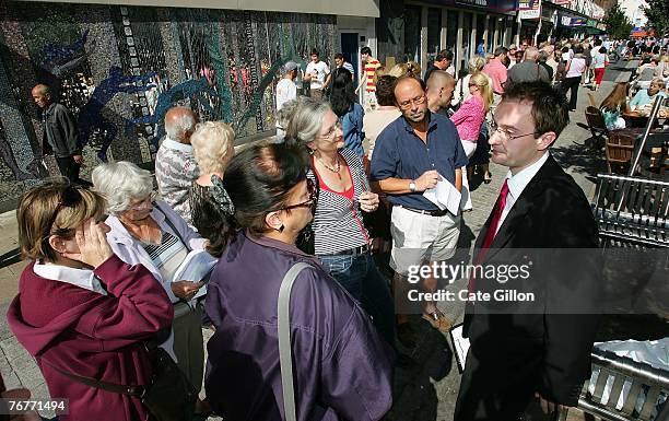 Bank assistant speaks to customers who wish to take their money out of their accounts with Northern Rock in a queue outside the Kingston branch of...