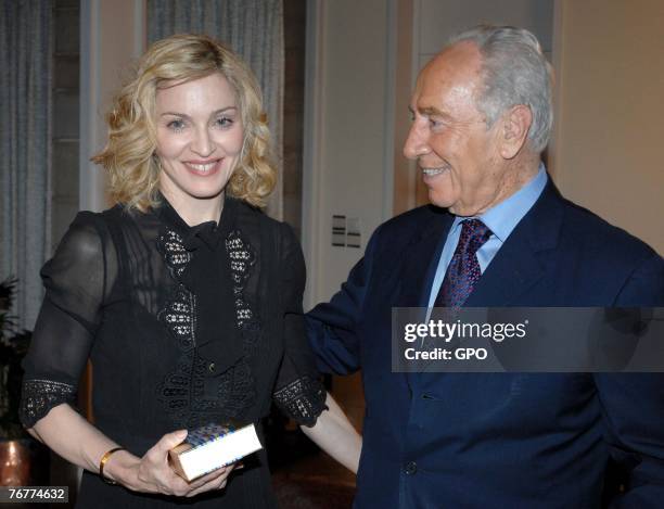 In this handout provided by the Israeli Government Press Office , actress and singer Madonna presents Israeli President Shimon Peres With a Kabbalah...