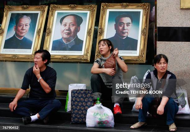 Chinese shoppers rest in front of the portraits of former Chinese Communist Party leaders Zhou Enlai , Mao Zedong and Liu Shaoqi at a popular...