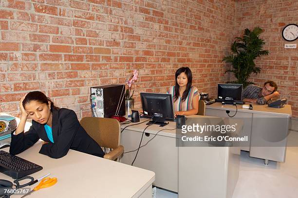 three people sitting at desks - 50er stock pictures, royalty-free photos & images
