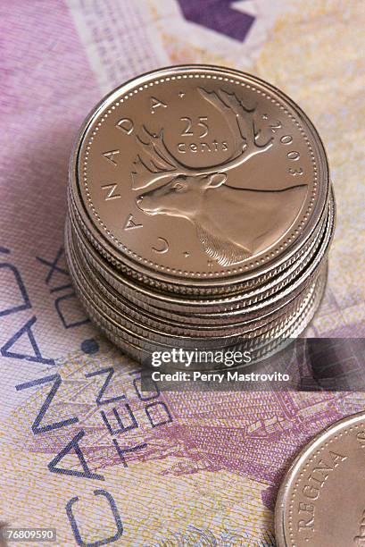 stack of canadian twenty-five cent coins on a bank note - five cent coin stockfoto's en -beelden