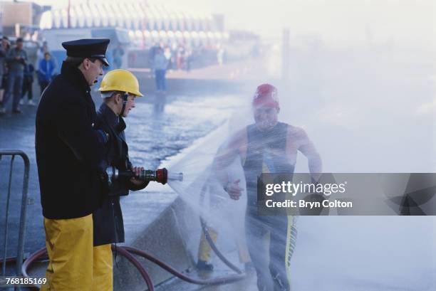 Competitor in the Hunstanton Triathlon exits the sea and is sprayed down with clean water by the Fire Brigade while on the sea front promenade, the...