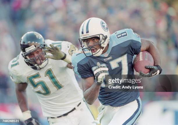 Kevin Dyson, Wide Receiver for the Tennessee Titans runs the ball out of reach of Kevin Hardy Linebacker for the Jacksonville Jaguars during their...