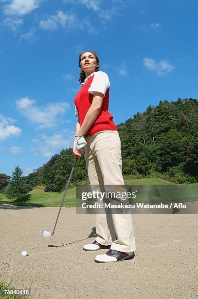 woman contemplating before playing a bunker shot - golf bunker low angle stock pictures, royalty-free photos & images