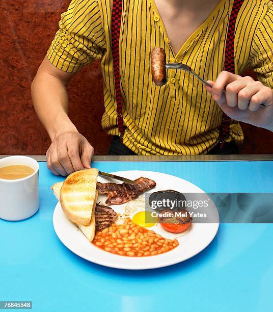 young man eating fried breakfast in cafe, mid section - english breakfast stock pictures, royalty-free photos & images