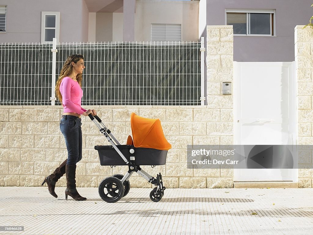 Mother pushing pram on pavement, Alicante, Spain,