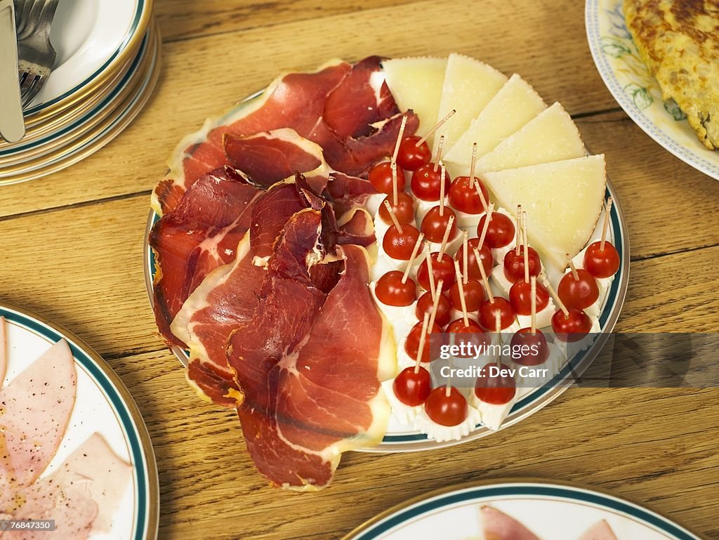 Plate of cured ham and cheese on table, close-up