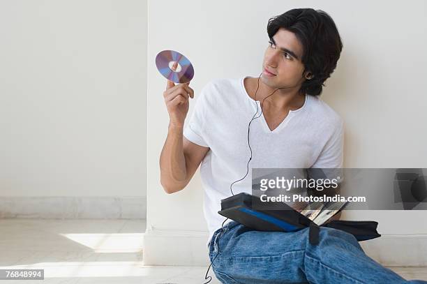 young man listening to music and holding a cd - personal compact disc player 個照片及圖片檔