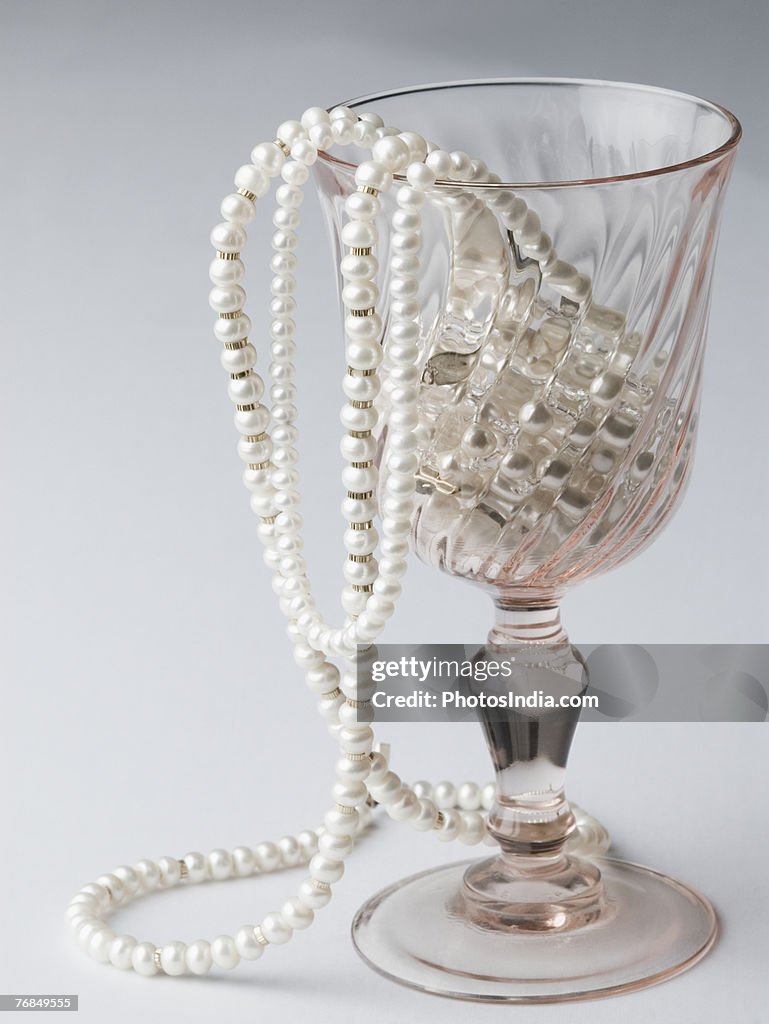 Close-up of pearl necklaces in a wine glass