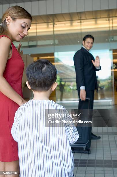 businessman waving to his wife and son at an airport - interracial wife photos stock-fotos und bilder