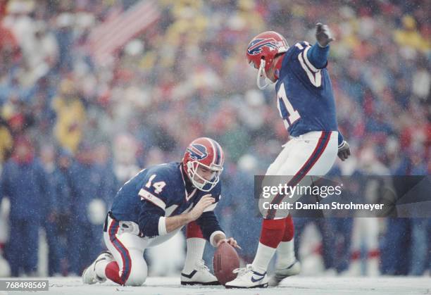 Quarterback Frank Reich holds the ball as Scott Norwood and Kicker for the Buffalo Bills attempts a field goal in the snow during their American...