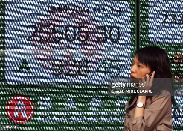 Woman walks past a board displaying the Hang Seng Index at the close of morning trade in Hong Kong 19 September 2007. Hong Kong share prices closed...