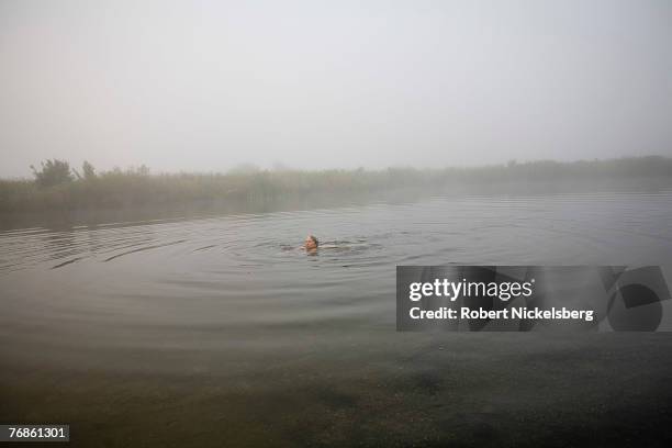 Woman swims in a pond in the early morning in EcoVillage at Ithaca in Ithaca , New York August 27, 2007. Many families were attracted to EVI by the...