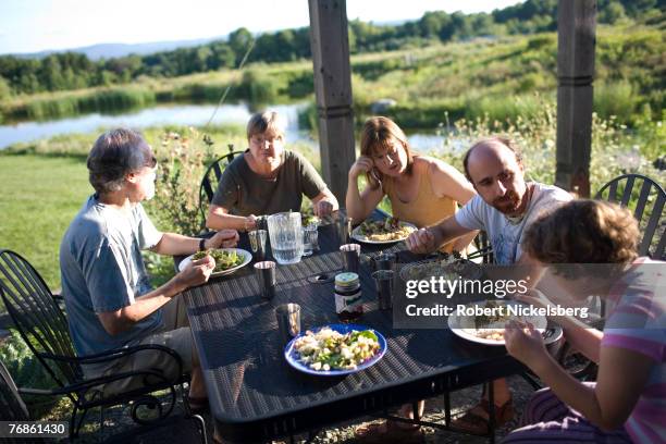 Residents of EcoVillage at Ithaca share a dining table outside the community's common house in Ithaca, New York August 27, 2007. EVI is situated on a...