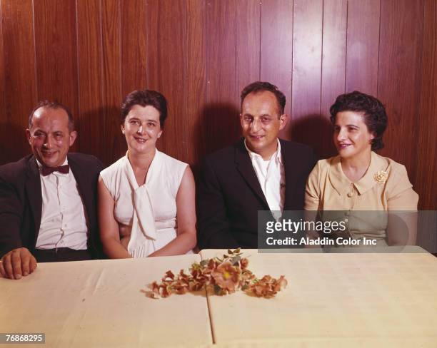 Two couples smile from behind a table at Belvedere Manor, New York, 1960s.