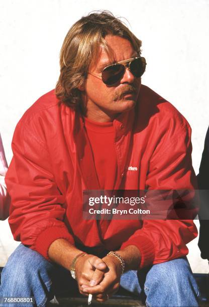 Finnish Formula One racing driver Keke Rosberg, of the McLaren-TAG team, sits on the wall of the pit lane ahead of the 1986 Australian Grand Prix at...