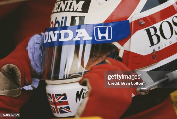 British Formula One racing driver Nigel Mansell wipes his visor as he sits in his car on the starting grid at the 1986 Australian Grand Prix at the...