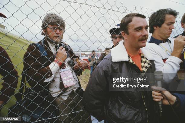 British Formula One racing driver Nigel Mansell , is pressed back against a wire fence by the media, as he holds an impromptu press conference after...