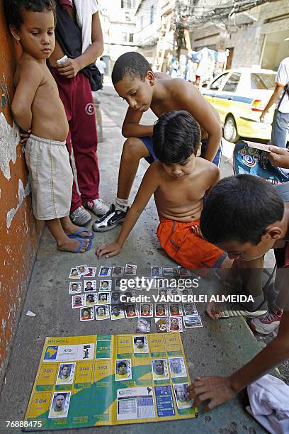 Children stick picture cards on an album of the players taking part in Germany 2006 World Cup, at Rio de Janeiro's Rocinha favela on April 2006. AFP...