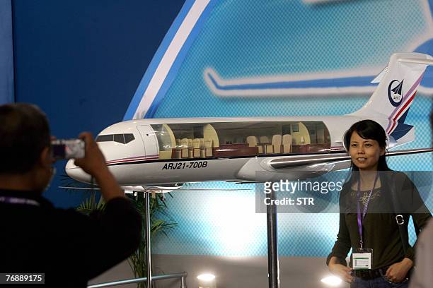 Chinese visitors pose for photo with a model of the ARJ21, the first civilian jet developed by China, at an aviation expo in Beijing 19 September...