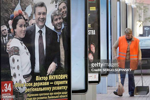 Communal service worker cleans around billboards of the pre-election ads for the pro-Russian Regions party of Prime minister Viktor Yanukovich 20...