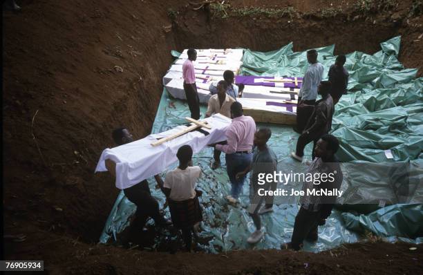 Men handle coffins into a mass grave in December of 1996 in Rwanda, Africa. In 1994 Rwanda saw one of the worlds worst act genocide to date. At least...
