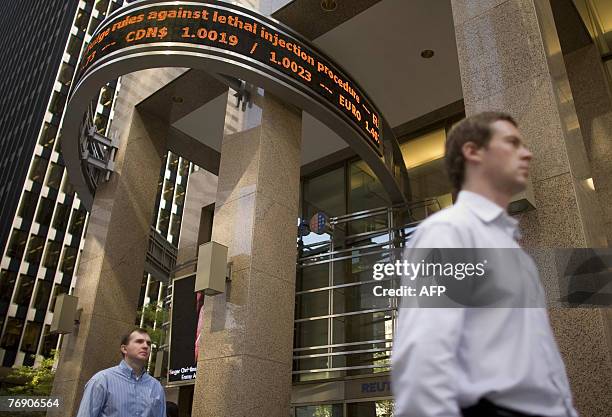 Office workers in downtown Toronto walk by a stock ticker 20 September, 2007 as the Canadian dollar hovers close to parity with the US Dollar. For a...