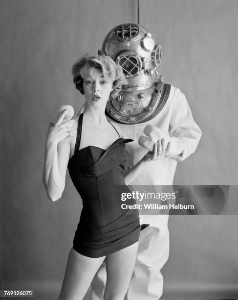 American model Jean Patchett , in a maillot swimsuit, holds hands with an unidentified male model, who stands behind her, in standard diving dress,...