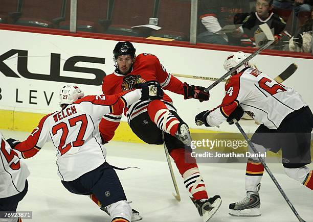 Troy Brouwer of the Chicago Blackhawks is knocked off his skates by Noah Welch and Stefan Meyer of the Florida Panthers during a preseason exhibition...