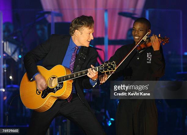 Personality Conan O'Brien and a Save The Music student perform during the VH1 Save The Music Foundation Gala at the Tent at Lincoln Center on...