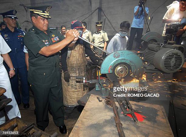 Armed forces chief General Hermogenes Esperon cuts a seized M-60 machine gun during a ceremony on the demilitarization of more than 32,000 captured...