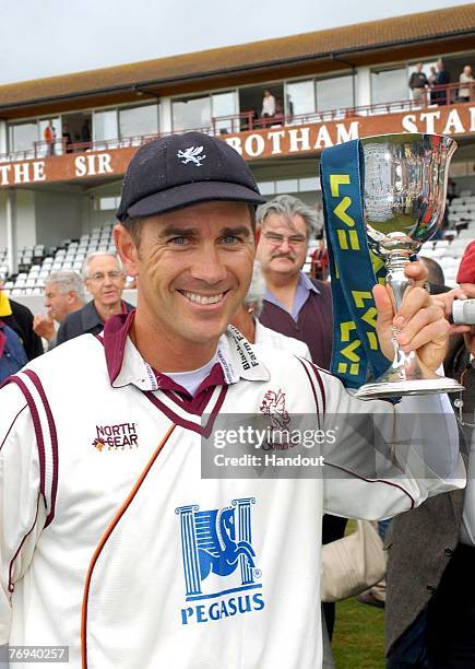 In this handout photo supplied by the ECB, Somerset captain Justin Langer celebrates with the LV League Two County Championship Trophy, after...