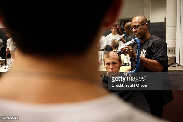 United States Navy recruit Gregory Stires of Orlando, Florida has his hair removed by barber Alvin Tharbs while being processed for boot camp at...