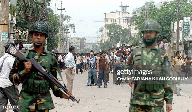 Bangladeshi soldiers stand guard on a road during a demonstration by garment workers in Dhaka, 22 September 2007. At least 25,000 textile workers...