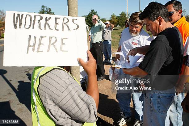 Day laborer representative Augusto Hernandez organizes the workers list with Daniel Pena as Bill Threlkeld , Director of former Herndon Official...