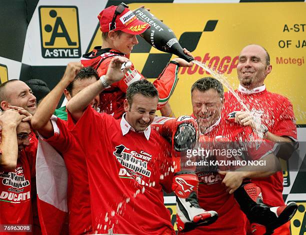 Casey Stoner of Australia , Ducati Marlboro team, sprays champagne over his teammates as he celebrates his first world motorcycling championship...