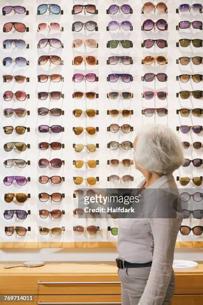 side view of senior woman choosing sunglasses at store - choosing eyeglasses stock pictures, royalty-free photos & images