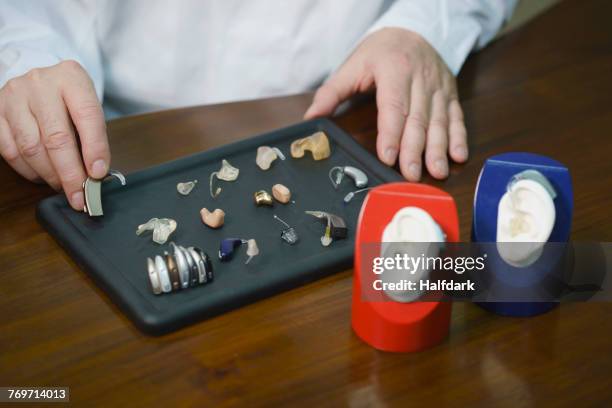 midsection of audiologist various hearing aids at table in doctors office - hearing aids stock pictures, royalty-free photos & images