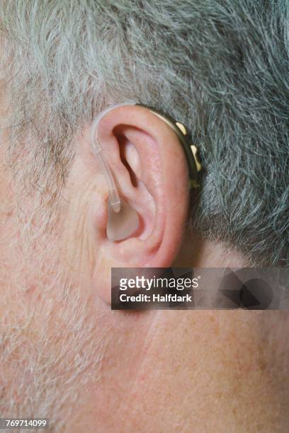 cropped image of man wearing hearing aid - ear canal stock-fotos und bilder