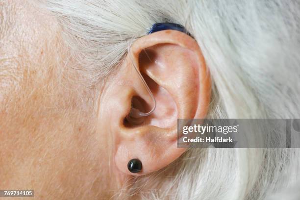 close-up of woman with gray hair wearing hearing aid - orelha humana - fotografias e filmes do acervo