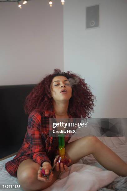young woman smoking a bong - bong stockfoto's en -beelden