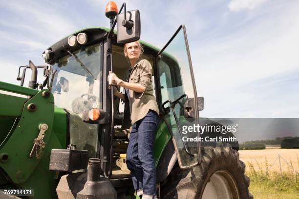 low angle view of woman standing on tractor at farm against sky during sunny day - bauer traktor stock-fotos und bilder