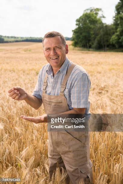 portrait of happy farmer holding wheat while standing at field in farm - corporate portraits depth of field stockfoto's en -beelden