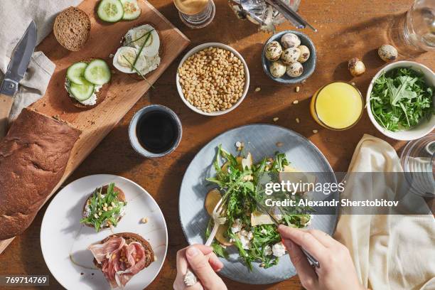 cropped image of man mixing salad with fork and table knife in plate on table - uovo di quaglia foto e immagini stock