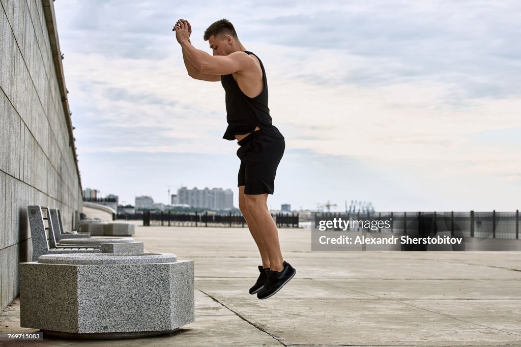 Side view of young male athlete jumping on footpath against sky, Blagoveshchensk, Amur, Russia