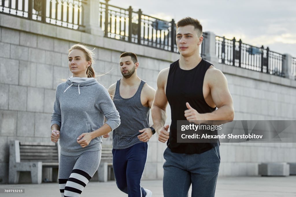 Young athletes jogging against bridge