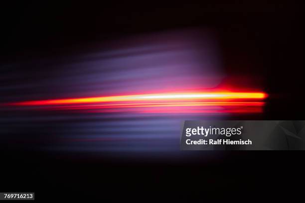 close-up of abstract red light trail against black background - velocità foto e immagini stock
