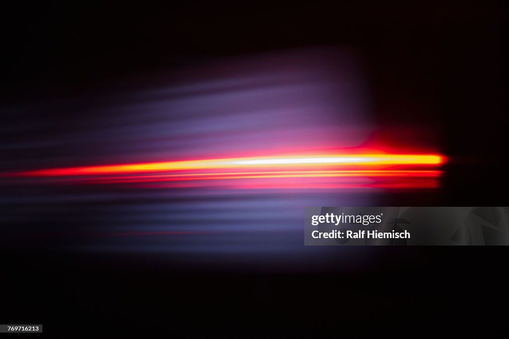 Close-up of abstract red light trail against black background