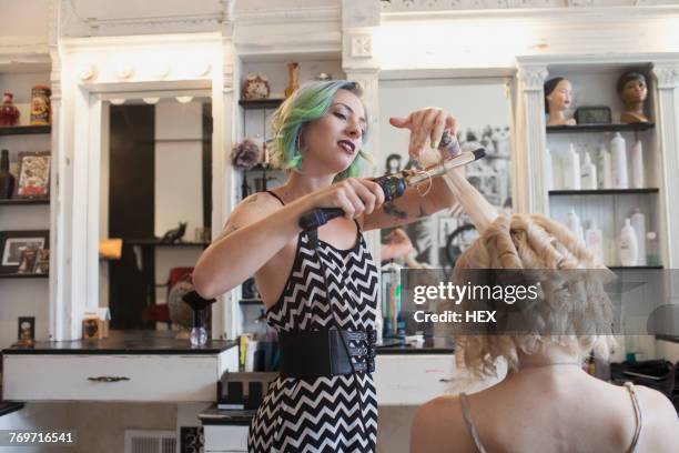 a hair dresser styling a customers hair. - hair curlers stock-fotos und bilder